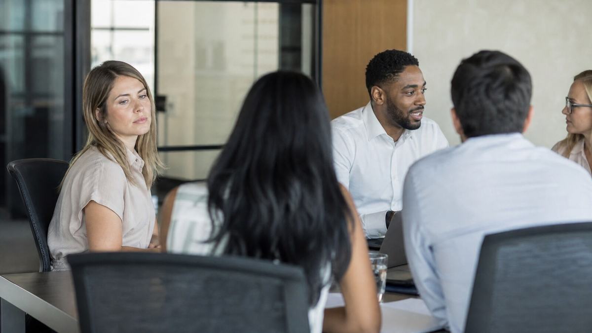 Diverse team in a workplace meeting, one colleague appearing isolated