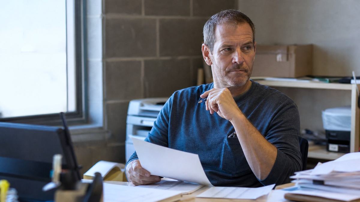 Worker reviewing documents while deciding to report workplace wrongdoing
